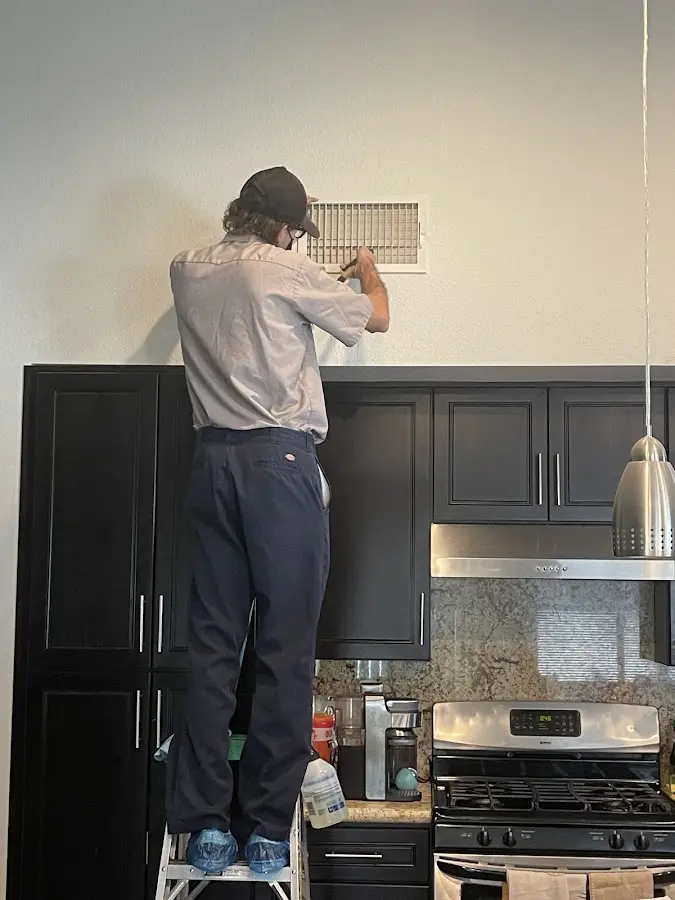 Technician inspecting an air vent during HVAC service in Tucson Mountains